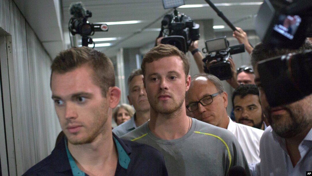 Dua perenang Olimpiade AS, Gunnar Bentz (kiri) dan Jack Conger meninggalkan kantor polisi di bandara Rio de Janeiro, Rabu (18/8). (AP/Mauro Pimentel)