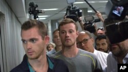 Dua perenang Olimpiade AS, Gunnar Bentz (kiri) dan Jack Conger meninggalkan kantor polisi di bandara Rio de Janeiro, Rabu (18/8). (AP/Mauro Pimentel)