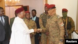 Mahamadou Issoufou, former president of Niger and head of the Economic Community of West African States (ECOWAS) delegation shakes hands with Burkina Faso's new military leader Ibrahim Traore during a meeting in Ouagadougou, October 4, 2022. 