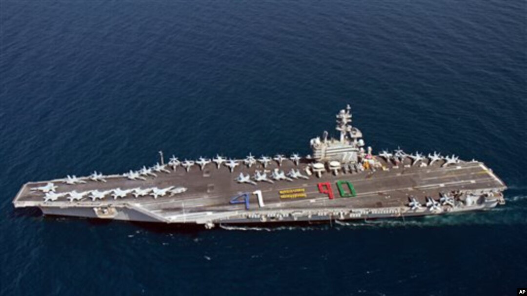 El portaaviones USS George H.W. Bush navega acompañado por un crucero y un destructor, ambos dotados con lanzamisiles.