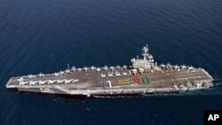 El portaaviones USS George H.W. Bush navega acompañado por un crucero y un destructor, ambos dotados con lanzamisiles.