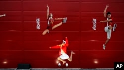 FILE - A young girl mimics the pose of a Chinese Olympic athletes depicted in Coca-Cola advertising, at the Olympic green in Beijing, Aug. 20, 2008. 