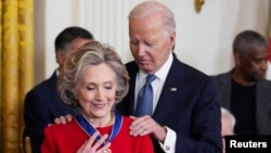 O Presidente dos EUA, Joe Biden, entrega a Medalha Presidencial da Liberdade à antiga Secretária de Estado dos EUA, Hillary Clinton, durante uma cerimónia na Sala Leste da Casa Branca, em Washington, EUA, a 4 de janeiro de 2025