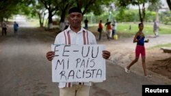 U.S. citizen William Potts poses with sign that says "USA my racist country" in Spanish, Havana, Cuba, Oct. 25, 2013.