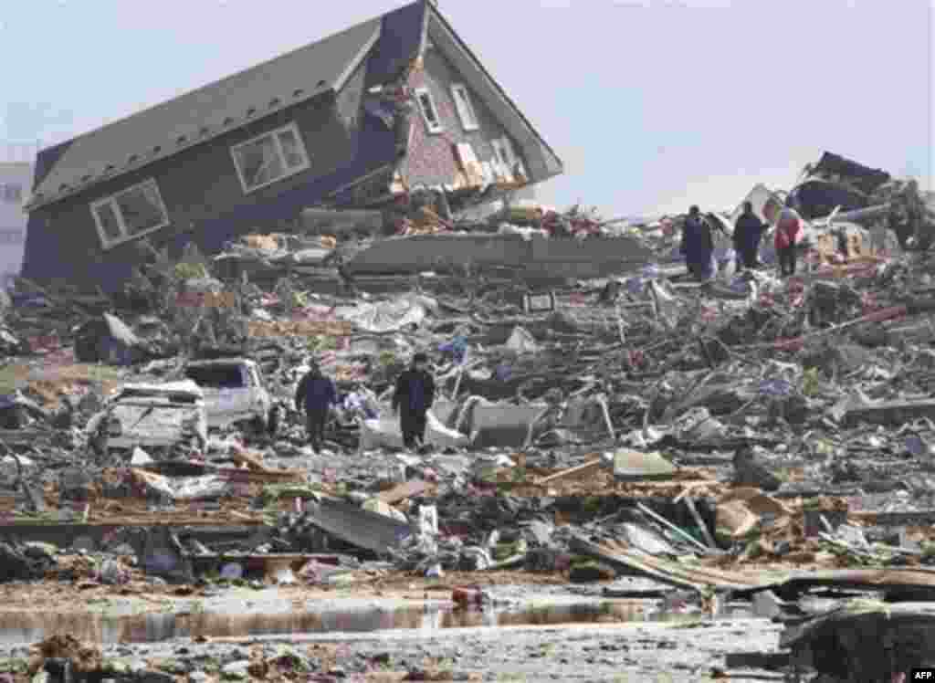 CORRECTS SOURCE - In this March 13, 2011 photo, people look at the upper part of a house washed away by tsunami in Minamisanrikucho in Miyagi Prefecture, two days after a powerful earthquake-triggered tsunami hit the country's northeast coast. (AP Photo/T