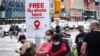Un anuncio ofrece vacunas gratuitas contra la gripe mientras gente camina durante una protesta en Brooklyn, Nueva Yor, el 21 de agosto de 2020.