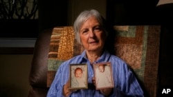 FILE - Peg Reif holds pictures of her children adopted from South Korea in the 1980s in her home Dec. 17, 2024, in Platteville, Wis. 