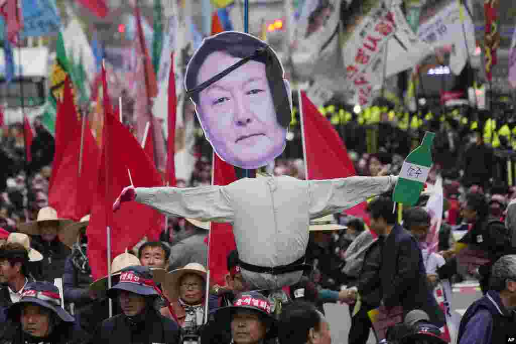 Anggota federasi petani nasional dan Konfederasi Serikat Buruh Korea berbaris membawa patung Presiden Korea Selatan Yoon Suk Yeol selama unjuk rasa untuk menuntut penangguhan impor beras dan pengunduran diri Yoon di Seoul, Korea Selatan. (AP)&nbsp;