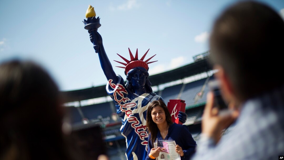 Brehisy Zuniga dari Meksiko berfoto dengan patung Liberty tiruan setelah menjalani upacara naturalisasi menjadi warga negara AS di Turner Field, Atlanta (16/9). (AP/David Goldman)