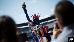 Brehisy Zuniga dari Meksiko berfoto dengan patung Liberty tiruan setelah menjalani upacara naturalisasi menjadi warga negara AS di Turner Field, Atlanta (16/9). (AP/David Goldman)