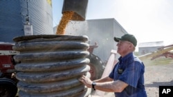FILE - A farmer checks on the operation of an auger transferring corn on his farm in Pawnee City, Nebraska, July 12, 2018. 
