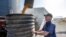 FILE - A farmer checks on the operation of an auger transferring corn on his farm in Pawnee City, Nebraska, July 12, 2018. 