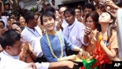 Aung San Suu Kyi, center, is surrounded by supporters after she cuts a ribbon to open the Aung San Jar-mon Library on Sunday, Aug. 14, 2011, in Bago, Burma.