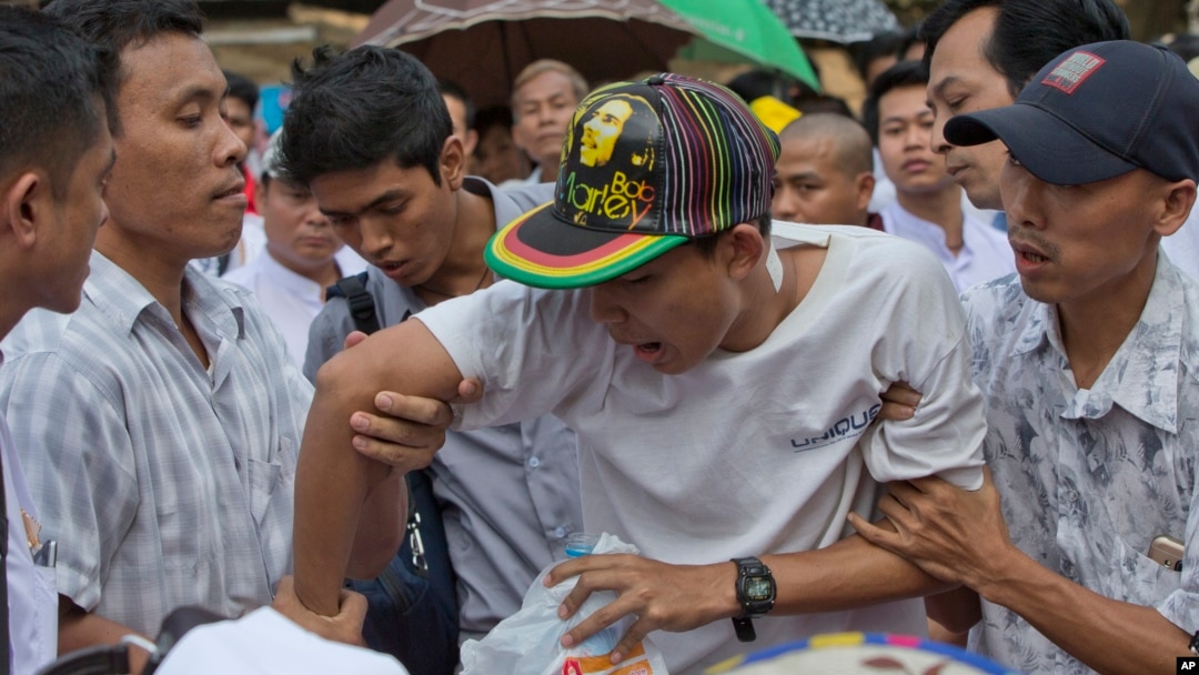 FILE - Having your arm twisted, physically, can hurt. Supporters of nationalist Buddhist monks twist an arm of a youth who allegedly mocked a speaker during a protest rally in Yangon, Myanmar, Dec. 29 2015.