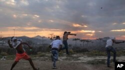 Para demonstran melemparkan batu ke arah pihak berwenang Venezuela, di perbatasan antara Brasil dan Venezuela, Sabtu, 23 Februari, 2019. (Foto: dok).