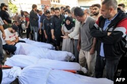 Ljudi se okupljaju kraj umotanih tijela žrtava koje su poginule u eksploziji u bolnici Ahli Arab u centralnoj Gazi 18. oktobra 2023.