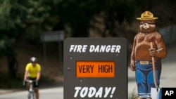 FILE - A Smokey Bear "Very High" fire danger sign is posted at the entrance to Griffith Park in Los Angeles, Sept. 10, 2015. 