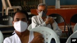 Indian men wait in an observation room after receiving the COVID-19 vaccine at a government hospital in Hyderabad, India, March 12, 2021. 