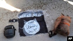 FILE - An Islamic State flag and other possessions from IS group fighters are seen in Hassakeh, Syria, Jan. 21, 2022. 