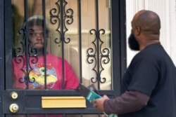 FILE - Anthony Brinson, right, talks with a resident while leaving a flyer at a home in Detroit, May 4, 2021. Officials are walking door-to-door to encourage residents of the majority Black city to get vaccinated against COVID-19.