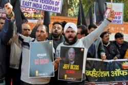 Members of the Confederation of All India Traders (CAIT) hold placards and shout slogans during a protest against the visit of Jeff Bezos, founder of Amazon, to India, in New Delhi, Jan. 15, 2020.