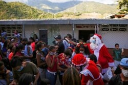 El Santa Claus de la ONG "Santa en las Calles" reparte alimento a residentes en un vecindario de pocos ingresos en Guarenas, Caracas, Venezuela, el 19 de diciembre de 2020.