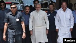 India's Prime Minister Narendra Modi (C) walks to speak with the media as he arrives to attend his first Parliament session in New Delhi, June 4, 2014. 