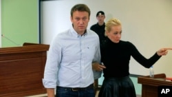 Pemimpin oposisi Rusia, Alexei Navalny (kiri) dan istrinya Yulia meninggalkan ruang pengadilan di Kirov, Rusia (16/10).