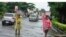 FILE - Women walk along a flooded street after a heavy downpour in Lagos, Nigeria, on July 10, 2024.