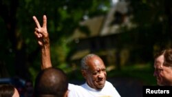 Bill Cosby flashes a "V" sign as he is welcomed outside his home after Pennsylvania's highest court overturned his sexual assault conviction and ordered him released from prison immediately, in Elkins Park, Pennsylvania, June 30, 2021. 