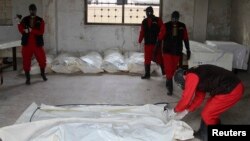FILE - Workers wrap the bodies of dead fighters loyal to Syrian President Bashar al-Assad at a morgue in Aleppo, Oct. 30, 2014. The opposition Free Syrian Army said it killed the men near Aleppo city and that some of the dead had Iranian and Afghan nationalities. 