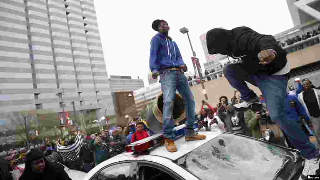 Para demonstran melompati mobil polisi dalam protes atas kematian Freddie Gray di tahanan polisi di Baltimore (25/4). ​(Reuters/Shannon Stapleton)