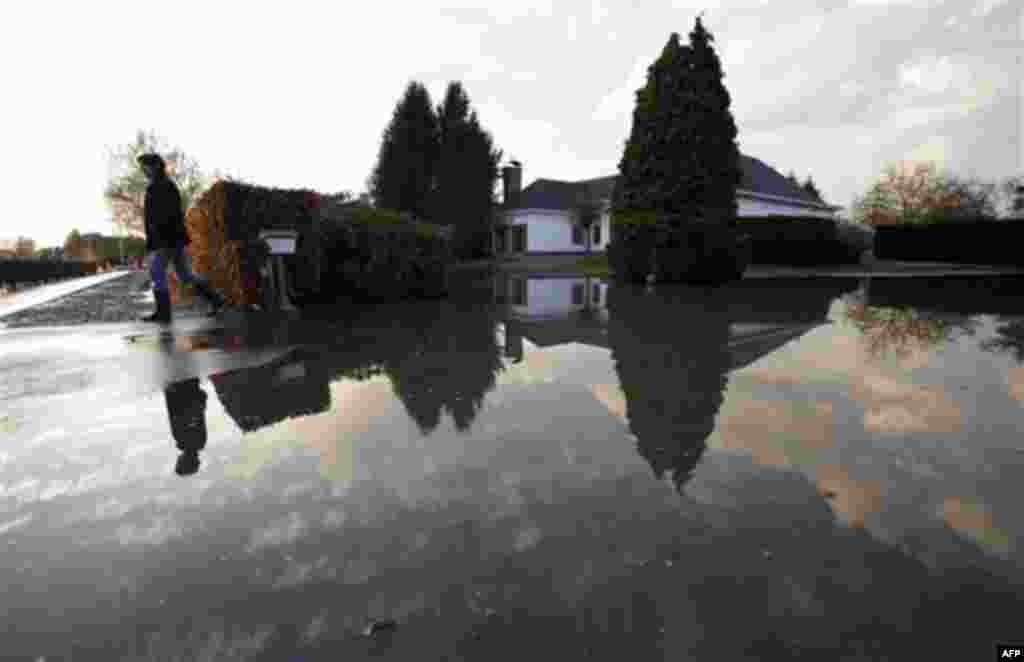 A woman stands in front of a flooded front lawn in Londerzeel, Belgium, on Monday, Nov. 15, 2010. Officials described the flooding over the weekend as the worst in 50-years. The national weather service said that in two days Belgium absorbed as much rainf