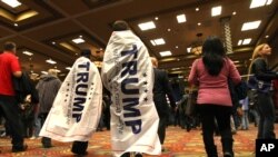 FILE - Two teens wearing Donald Trump banners walk into the Reno Ballroom and Museum prior to Republican presidential candidate Donald Trump's rally, Jan. 10, 2016.