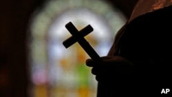 FILE - A silhouette of a crucifix is seen against the backdrop of a stained glass window inside a Catholic Church in New Orleans, Louisiana, Dec. 1, 2012.