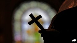 FILE - A silhouette of a crucifix is seen against the backdrop of a stained glass window inside a Catholic Church in New Orleans, Dec. 1, 2012.