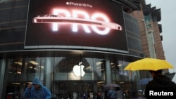 People walk past an Apple store on a rainy day as the new iPhone 16 series smartphones go on sale in Beijing, China, Sept. 20, 2024.