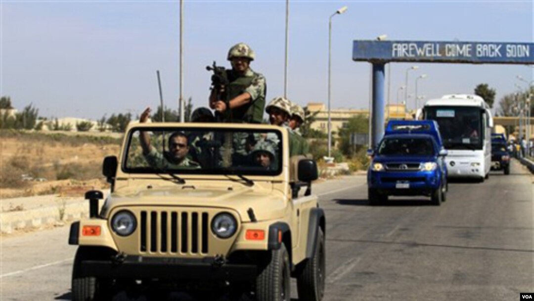 Tentara Mesir mengawal tahanan Palestina yang dibebaskan dari penjara dari penjara Israel ketika bis mereka melintas memasuki perbatasan Mesir (18/10).