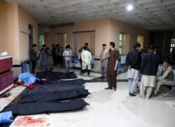 Afghan men look for their relatives as body bags are laid out at a hospital, following a suicide bombing in Kabul, Afghanistan, Oct. 24, 2020.