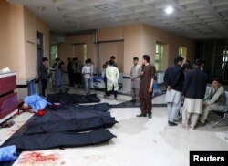 Afghan men look for their relatives as body bags are laid out at a hospital, following a suicide bombing in Kabul, Afghanistan, Oct. 24, 2020.