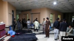 Afghan men look for their relatives as body bags are laid out at a hospital, following a suicide bombing in Kabul, Afghanistan, Oct. 24, 2020.