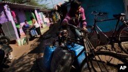 A resident fills plastic containers with drinking water at a slum in New Delhi, India. Engineers were working Tuesday on restoring New Delhi's full water supply after protesters damaged a key canal in a neighboring state and disrupted supplies over the weekend. (AP Photo/Bernat Armangue)