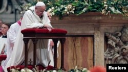 Pope Francis kneels as he leads the Christmas night Mass in Saint Peter's Basilica at the Vatican, Dec. 24, 2014.