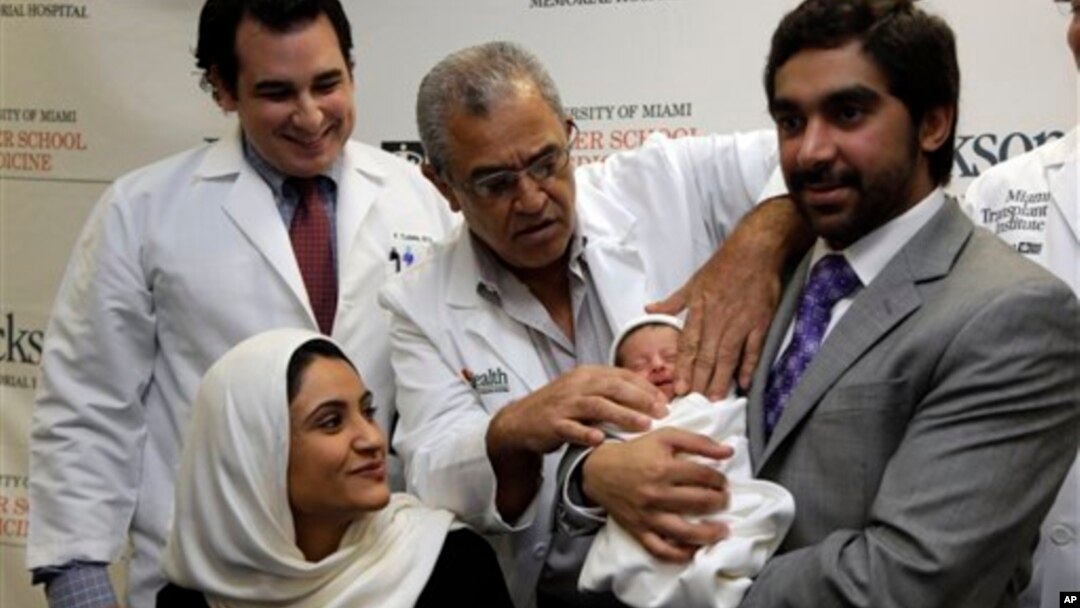 Fatema Al Ansari dari Qatar (kiri), melihat dokternya Salih Yasin merapikan kain pembungkus bayi yang digendong suaminya, Khalifa Alhayal di Rumah Sakit Jackson Memorial, Miami. (AP/Lynne Sladky)