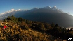 FILE - Trekkers watch the sun rise over the Annapurna Range, right, in central Nepal.