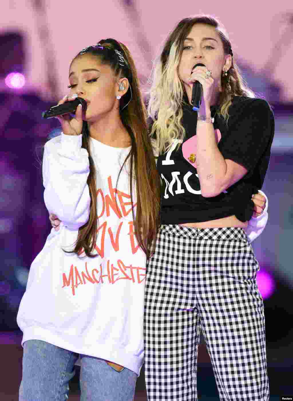 美国流行歌手爱莉安娜&middot;格兰德（Ariana Grande）和歌手、演员麦莉&middot;希拉（Miley Cyrus，右）在曼彻斯特慈善音乐会上演唱（2017年6月4日）。爱莉安娜的衣服上印着&ldquo;同一个爱&middot;曼彻斯特&rdquo;。麦莉&middot;希拉曾经主演过美国迪斯尼公司出品的青少年电视情景喜剧《孟汉娜》