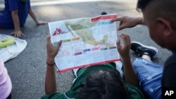 Migrants, who are part of a a caravan heading toward the country's northern border and ultimately the United States, check a map during a break, on the outskirts of Escuintla, southern Mexico, Nov. 7, 2024.