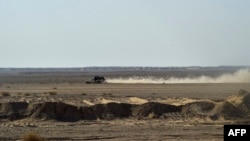 FILE - Afghan migrants ride in a pickup truck along a desert road toward the Iran border, Feb. 17, 2022. Dozens of Afghans were reportedly killed by Iranian forces while illegally crossing the border from Pakistan, a Taliban official said Oct. 16, 2024.