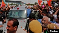 Narendra Modi, kandidat Perdana Menteri India dari partai Bharatiya Janata (BJP), memberikan 'salam damai' kepada para pendukungnya dari dalam mobil yang membawanya dari bandara New Delhi menyusuri pusat kota (17/5).