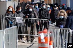 FILE - Patients wearing face masks and personal protective equipment wait on line for COVID-19 testing outside Elmhurst Hospital Center, March 27, 2020, in New York City.
